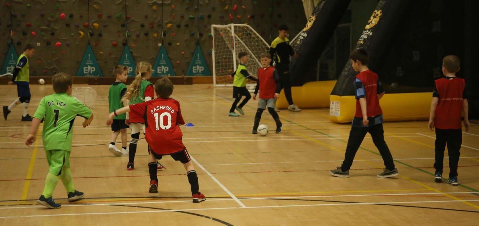 Children playing a football match in a sports hall at an FSS party